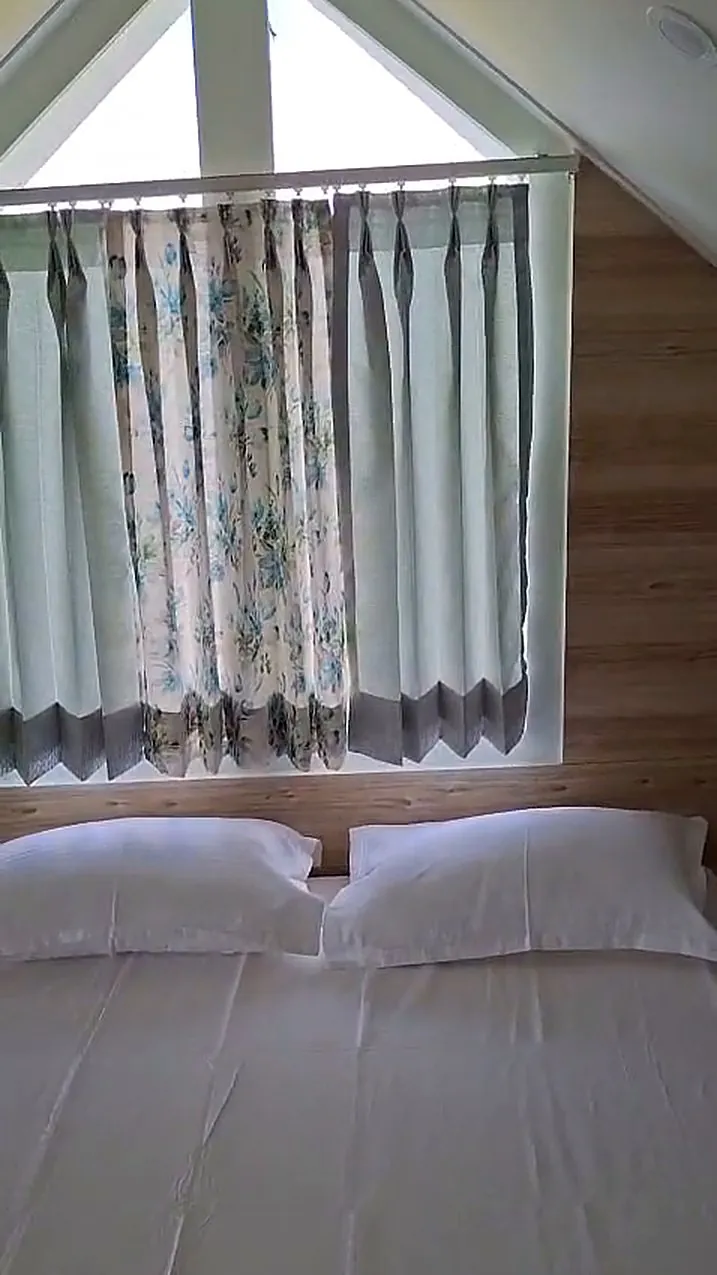 The attic room bed tucked under the gable window