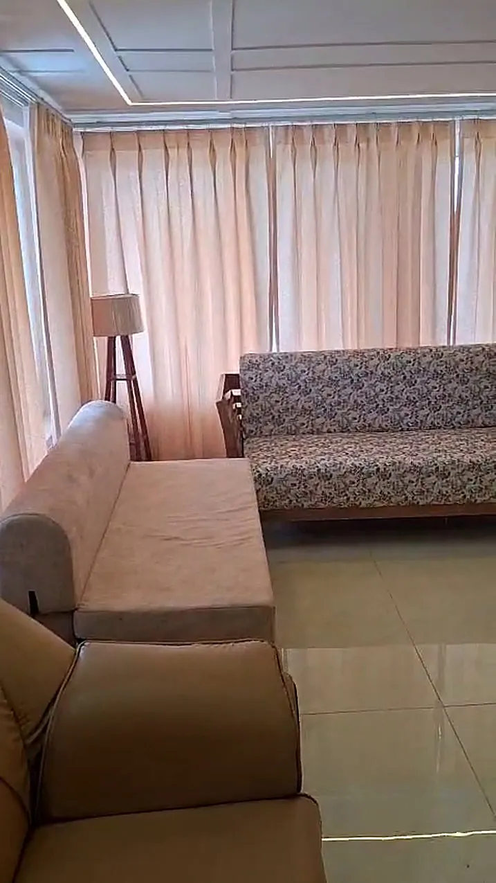 The lounge with sofas along a wall of curtained windows