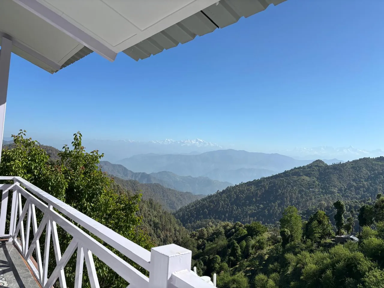 Summer view from the verandah over green hills to the Himalayas